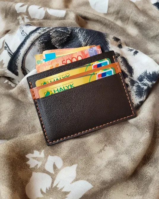 Кожаный кошелек с банковскими картами и деньгами на деревянном столе с осенними листьями