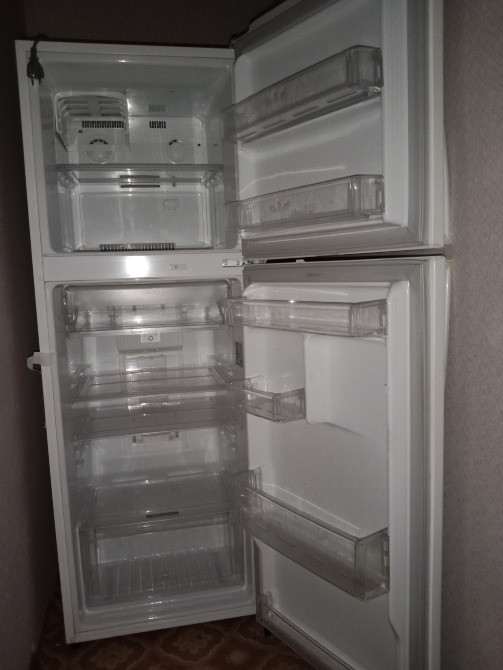 Холодильник с открытыми дверцами и пустыми полками