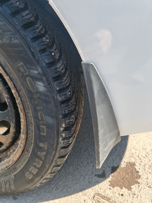 Ақ автокөліктің дөңгелегіндегі лай қорғанысы жақыннан