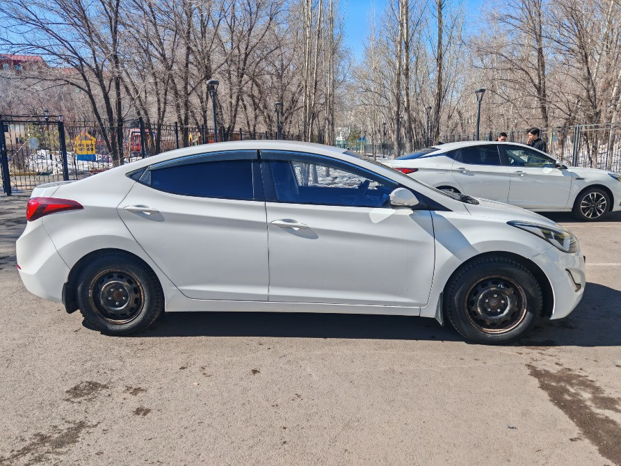 Ақ Hyundai Elantra автокөлігі ашық аспан астында бокстан