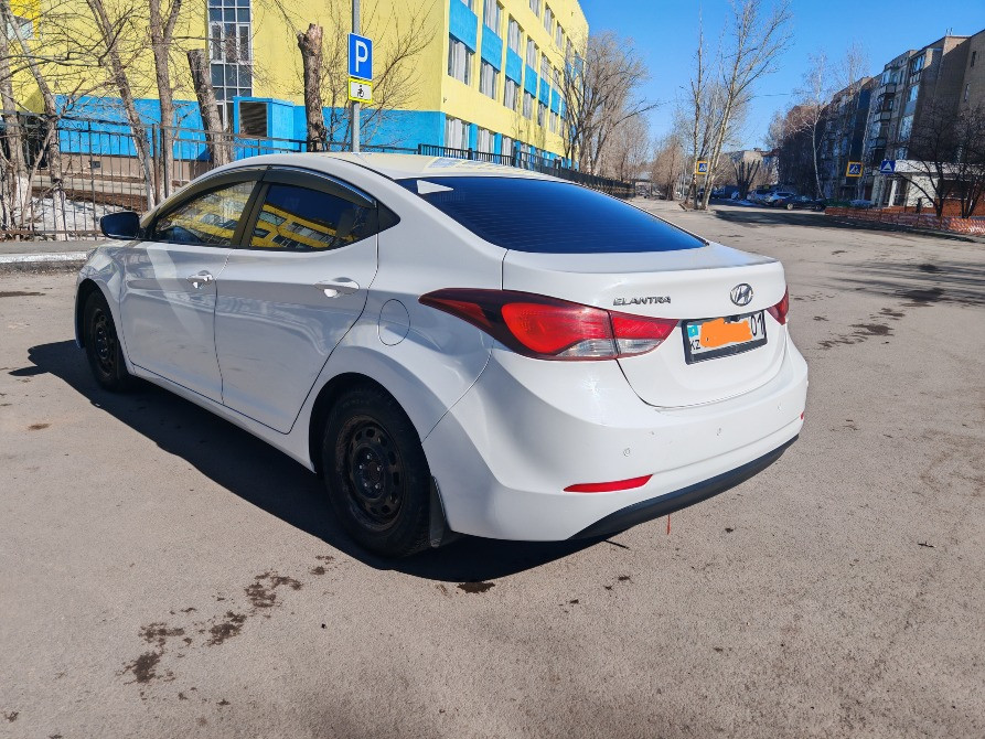 Тұрақтағы ақ Hyundai Elantra автокөлігінің артқы көрінісі