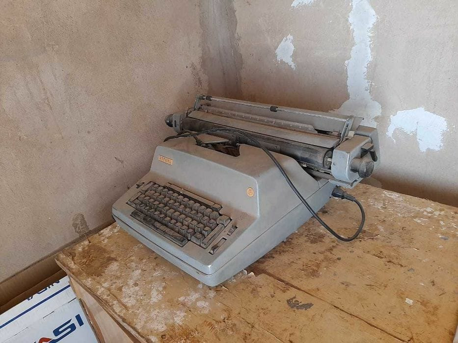 Ескі жазу аппараты голWalls қабырғалары бар бөлмеде үстелде тұр.