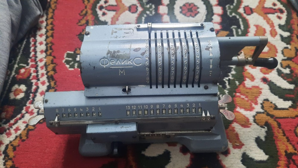 Ескі есептегіш аппарат Феликс түсті кілем үстінде