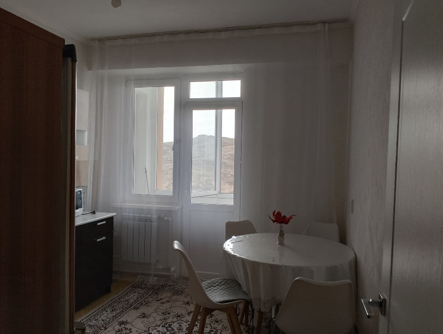 Фото кухни с обеденным столом и окном, оформленным шторами