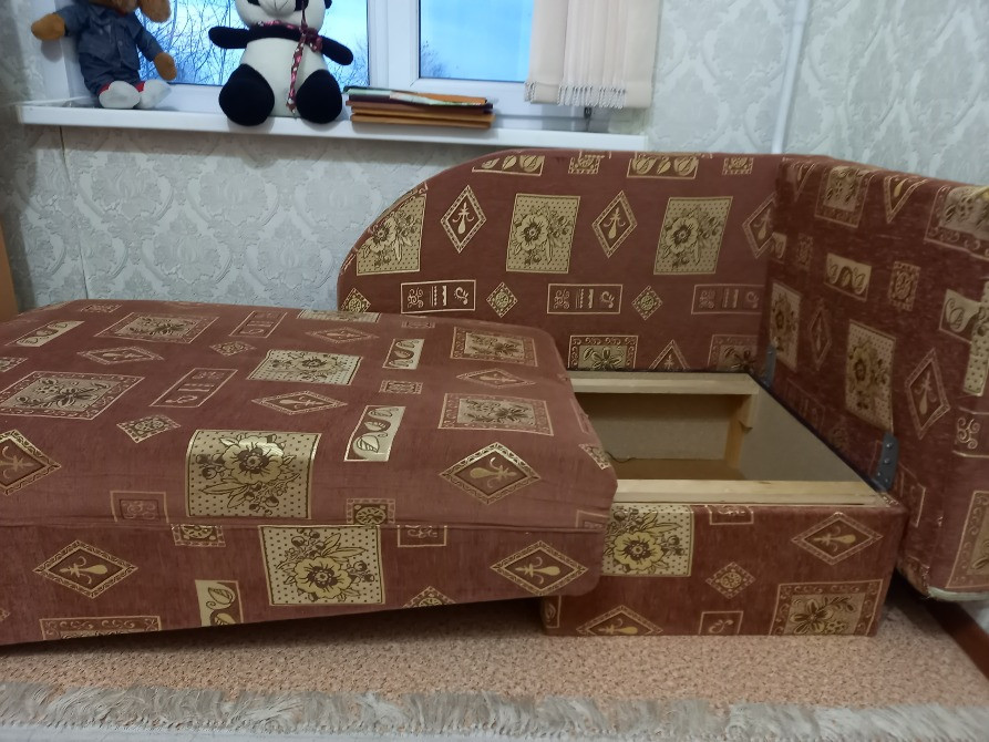 Выдвинутый механизм дивана, открывающий место для хранения, на фоне окна