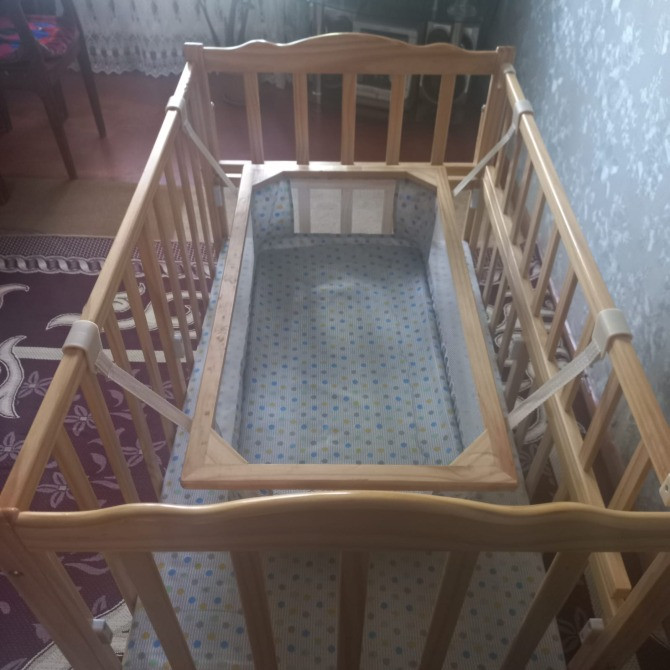 Вид сверху на детскую кроватку с сетчатыми боками и мягким покрытием