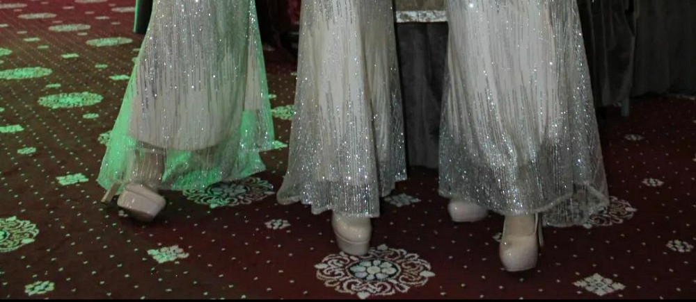 Две фигуры в сверкающих длинных платьях с блестками и высокими каблуками на ковровом покрытии