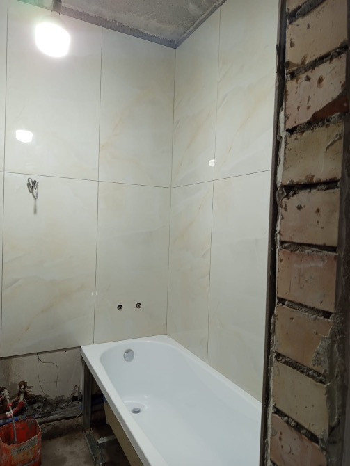 Ванна орнатылған және плиткамен қапталған қабырғалармен бос ванна бөлмесі