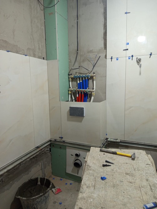 Ванна бөлмесінің жөндеу жұмыстарының аралық кезеңі, жылу және су құбырлары мен қабырғаларда плиткамен.