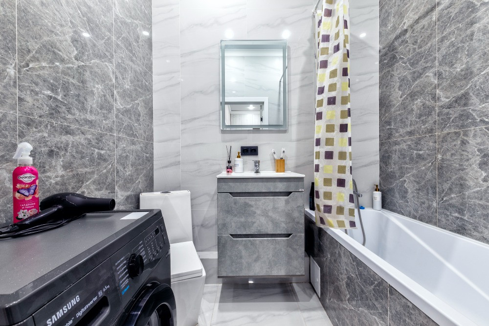 Уютная ванная комната с ванной и стиральной машиной