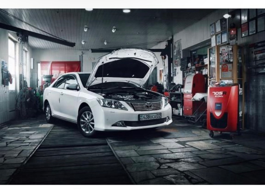 Автосервис алдындағы ашық капоты бар ақ автомобиль, диагностика құралдарымен жабдықталған фон