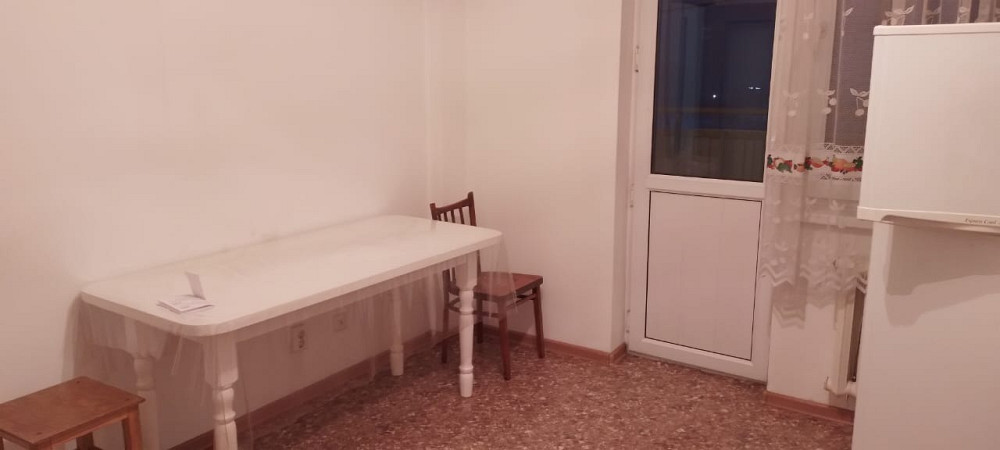 Кешкі жарықтағы ақ үстелі, тоңазытқышы мен терезелері бар асхана