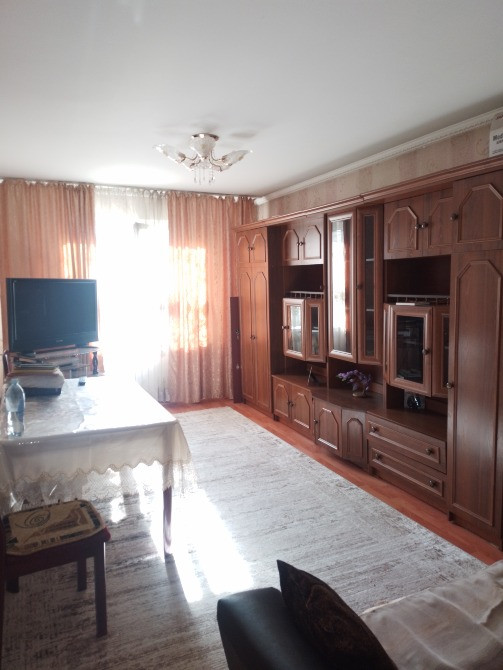 Ағаштан жасалған мебельдері мен теледидары бар қонақ бөлме