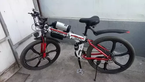 Қара-қызыл рама мен үлкен спицалары бар электрлік велосипед. Рамада аккумулятор мен электроника орналасқан.