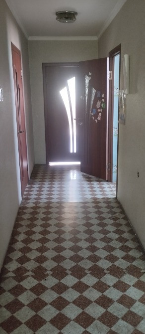 Ашық есік пен плиткалы едені бар коридор