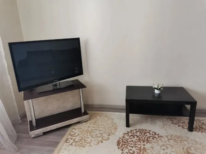 Қонақ бөлмесіндегі кофейный үстелдің жанына қойылған телевизор.