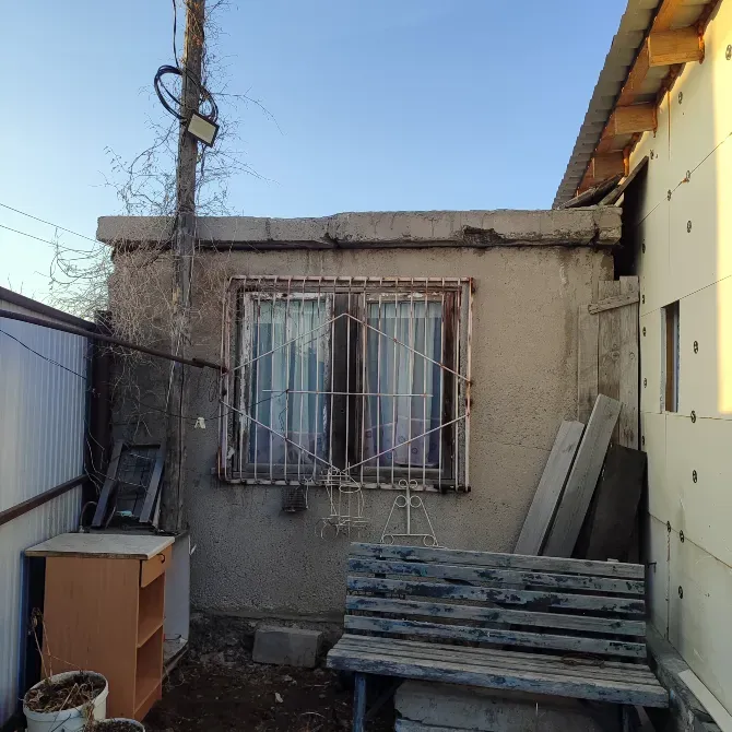 Кусок двора с бетонным домом и окном, на котором установлена решетка