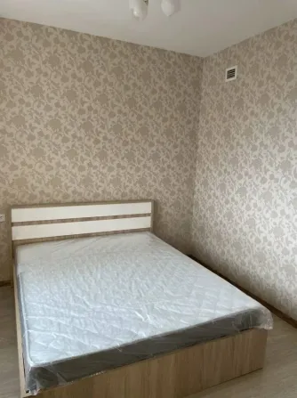 Бір орындық төсек және гүлді принтпен безендірілген жатын бөлме