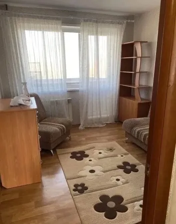 Комната с двумя креслами, полами из дерева и окнами с занавесками