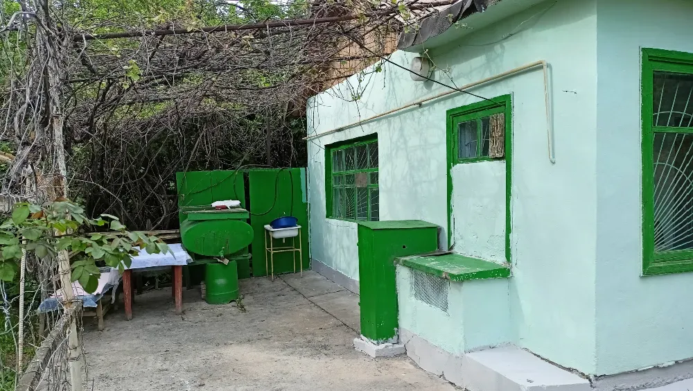 Дом с зелеными элементами и столом во дворе