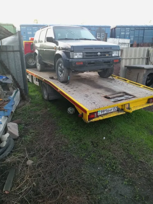 Грузовик с платформой, на которой находится черный внедорожник