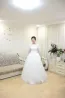 Көйлек киген қыз диванның жанындағы бөлмеде тұр