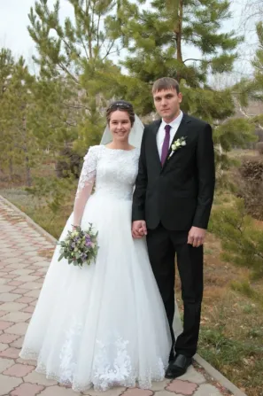Невеста мен жігіт ашық ауада, жасыл ағаштар арасында, гүл шоғын ұстап тұр