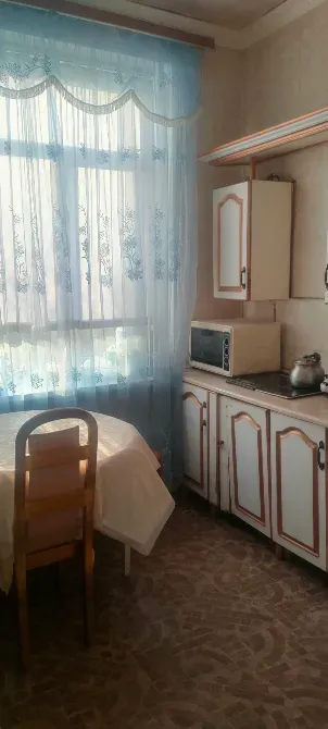 Кухня с окном, столом и плитой, оформленная в простом стиле