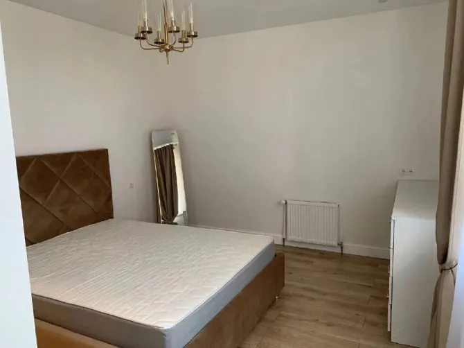 Нейтралды реңктерде безендірілген төсекті және айнасы бар жатын бөлме