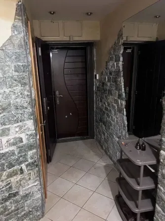 Прихожая с дверью и стенами, отделанными камнем
