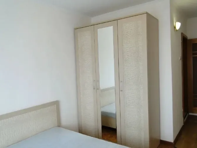 Екі кісілік төсек және айнасы бар шкафы бар жатын бөлме