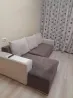 Сұр жастықтармен диван жарық бөлмеде гүлді перделермен