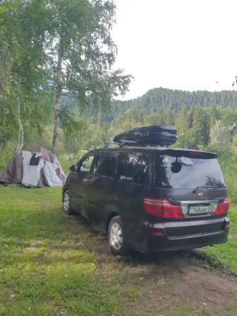 Черный микроавтобус рядом с палаткой на природе