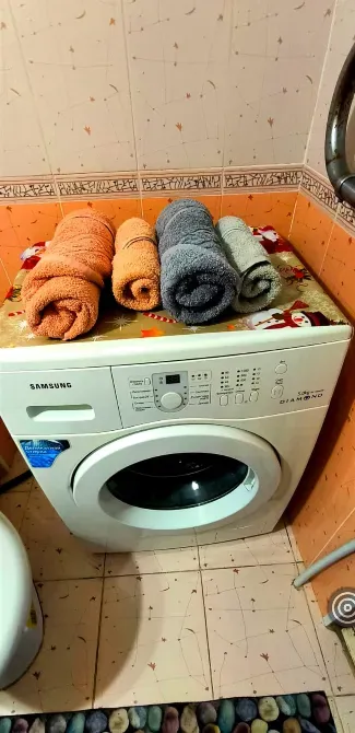 Стиральная машина с свернутыми полотенцами сверху