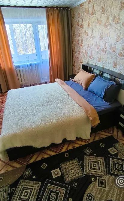 Спальня с двуспальной кроватью и окнами, оформленными шторами