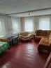 Диванмен және үстелмен жабдықталған бөлме; қызыл еден және перделермен жабдықталған терезелер