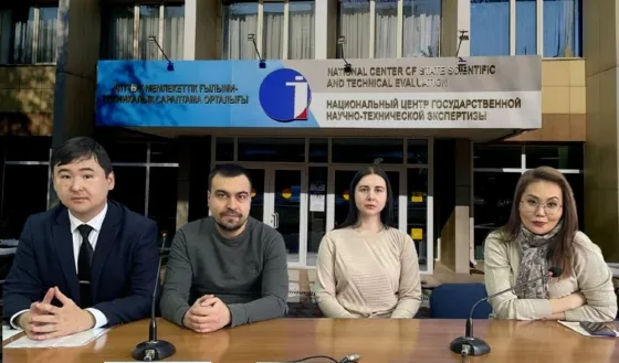 Группа людей в деловой обстановке перед зданием научного центра с надписями на английском и русском языках