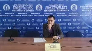 Неизвестный человек на фоне стенда с надписями на русском языке, занимается презентацией