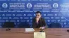 Белгісіз адам орыс тіліндегі жазулармен стендтың алдында презентация жасап жатыр