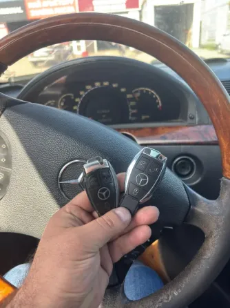 Ключи от автомобиля Mercedes-Benz, один с логотипом и кнопками, другой без значков