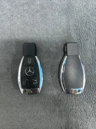 Mercedes-Benz автокөлігінің кілттері, біреуі логотипі мен батырмаларымен, екіншісі белгісіз.