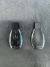 Mercedes-Benz автокөлігінің кілттері, біреуі логотипі мен батырмаларымен, екіншісі белгісіз.