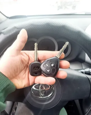 Ключи от автомобиля Toyota на фоне руля авто
