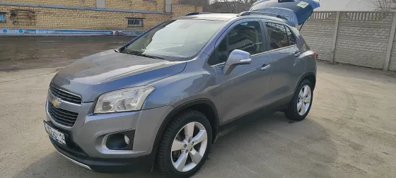 Автомобиль Chevrolet Trax серого цвета на парковке с открытой крышкой багажника