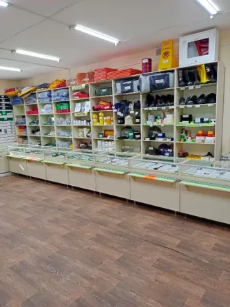 Внутренний вид магазина с витринами, заполненными товарами, включая рабочую одежду и хозяйственные принадлежности