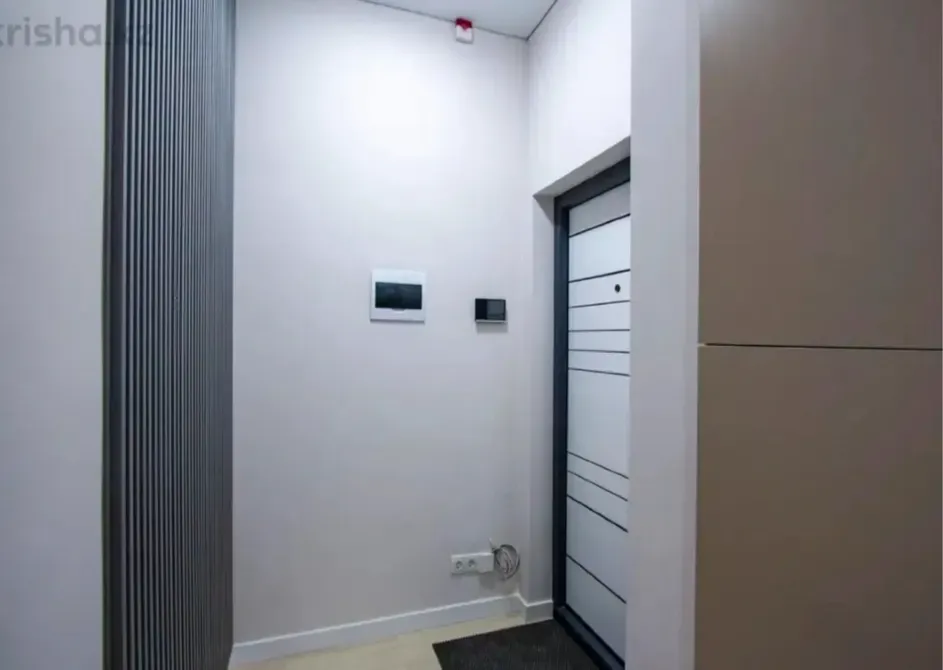 Кіру есігі және нейтральды тондармен безендірілген қабырғалары бар дәліз