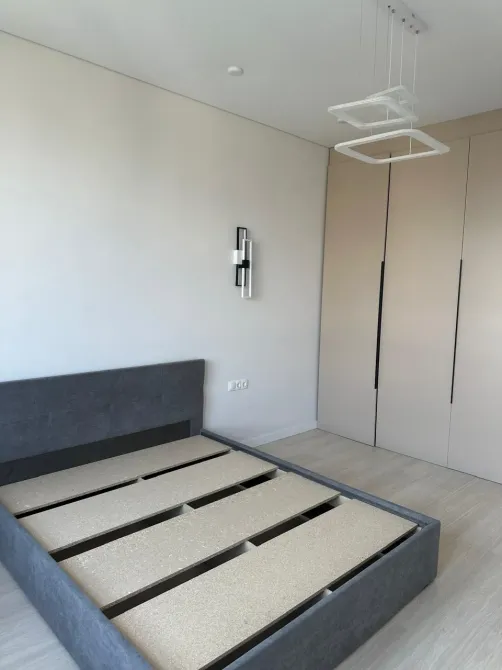 Интеграцияланған шкафтармен жабдықталған бос төсек бар ұйықтау бөлмесі