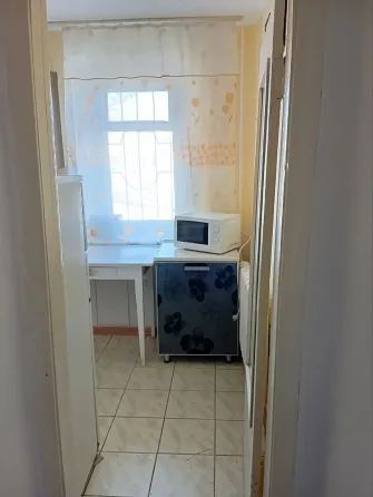 Кухня с микроволновой печью и холодильником, светлое помещение с окном