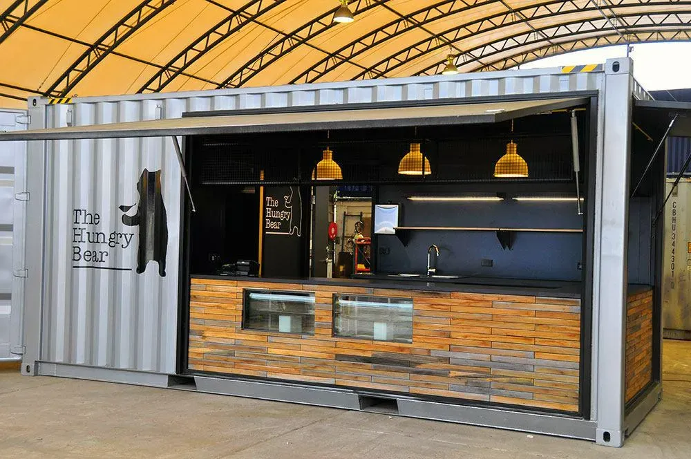 Ағаш әрлеуімен және стильді шамдарымен контейнерден жасалған кулинарлық киоск