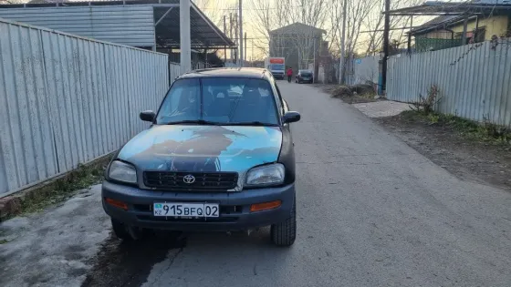 Вид спереди старинного внедорожника Toyota с графикой на капоте, припаркованного на узкой улице